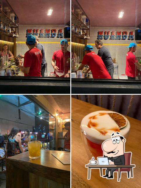 Sente em uma das mesas no Muamba Bar e Coquetéis