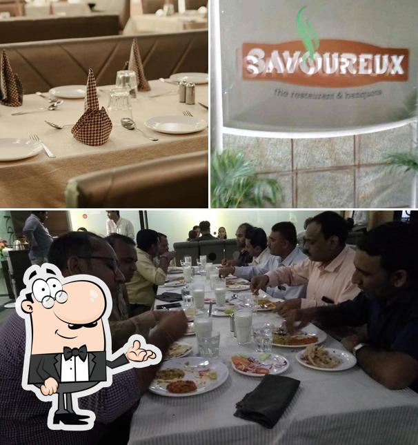 Take a seat at one of the tables at Savoureux The Restaurant & Banquet, Best Restaurant In Naranpura
