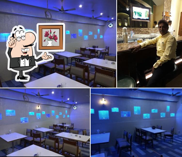 Take a seat at one of the tables at Hotel Supraja Savji Bar