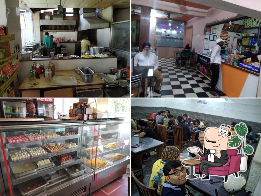Take a seat at one of the tables at Sharma Dhaba{Sharma Shudh Vaishno Dhaba Sweets & Fast Food}